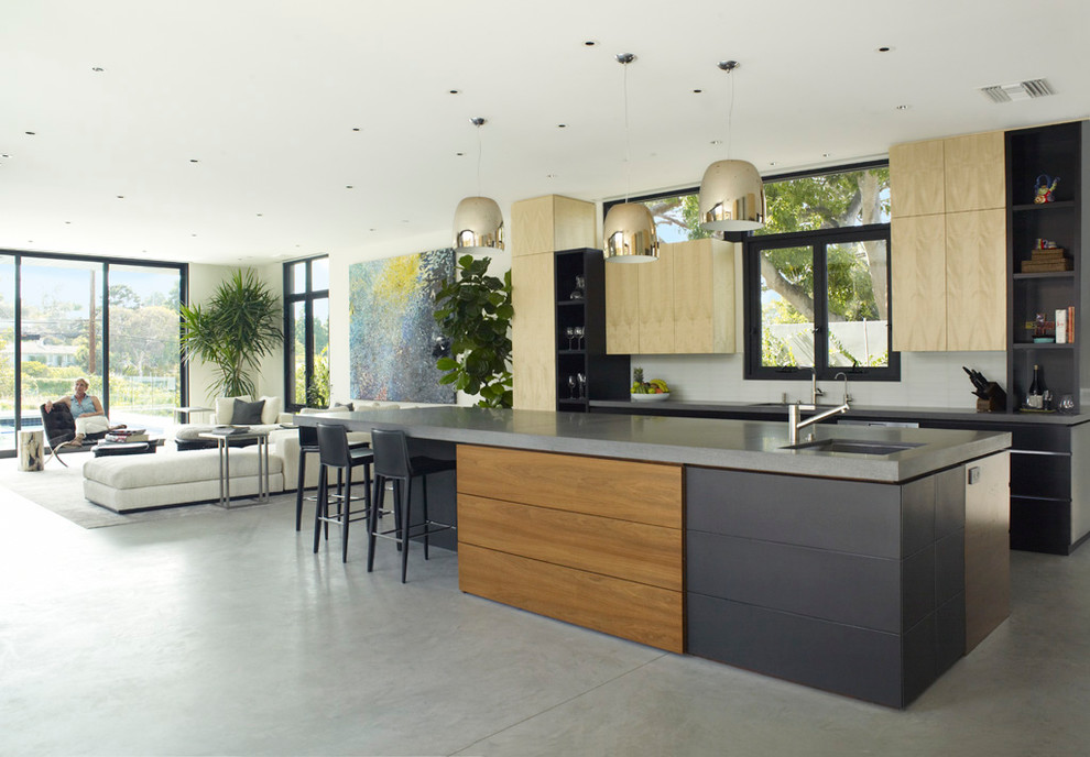 Offene Moderne Küche mit flächenbündigen Schrankfronten, hellen Holzschränken, Betonboden und Kücheninsel in Los Angeles