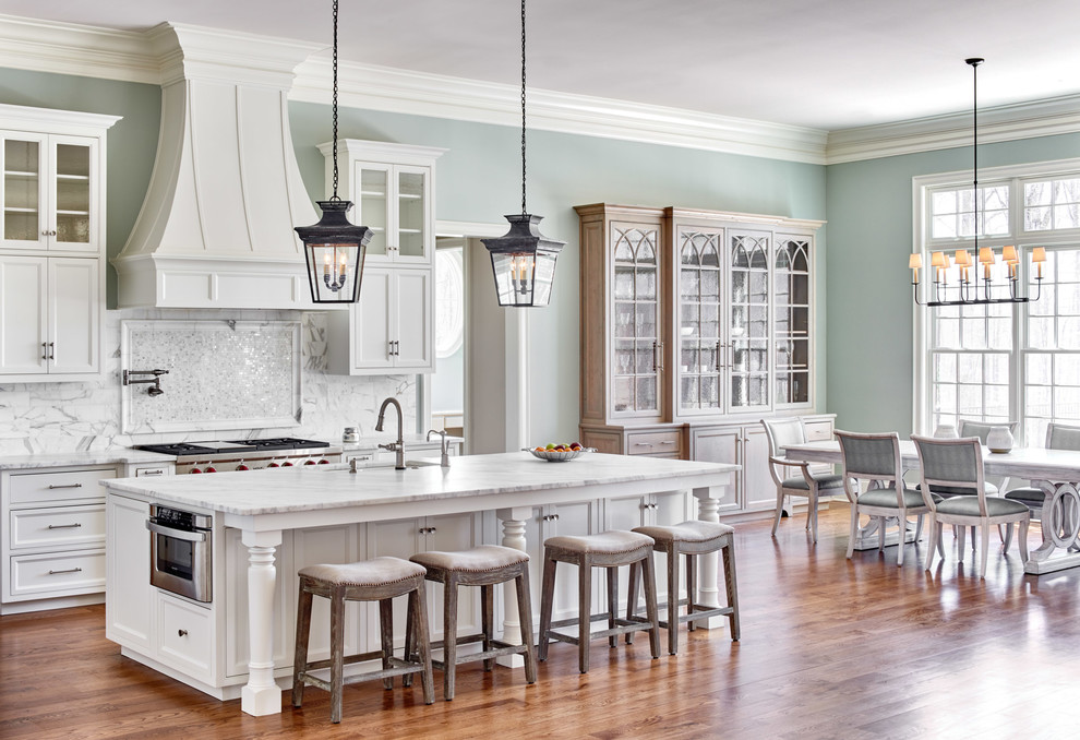Foto på ett stort vintage vit kök och matrum, med marmorbänkskiva, vitt stänkskydd, stänkskydd i marmor, rostfria vitvaror, mellanmörkt trägolv, en köksö, en undermonterad diskho, skåp i shakerstil och vita skåp