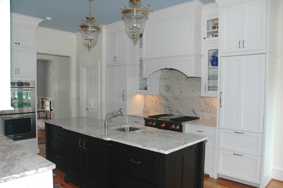 This is an example of a traditional kitchen in Raleigh with a submerged sink, beaded cabinets, white cabinets, quartz worktops, stone slab splashback, integrated appliances, medium hardwood flooring and an island.