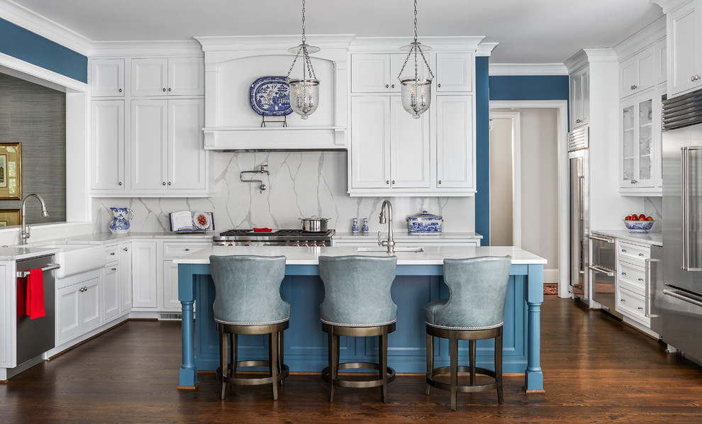 Example of a classic u-shaped dark wood floor and brown floor kitchen design in Atlanta with a farmhouse sink, recessed-panel cabinets, white cabinets, wood countertops, gray backsplash, stone slab backsplash, stainless steel appliances, an island and white countertops