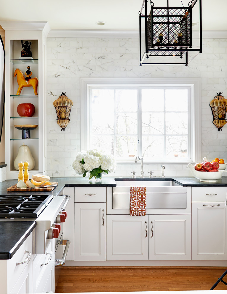 Klassische Küche in L-Form mit Landhausspüle, Kassettenfronten, Küchenrückwand in Weiß, Küchengeräten aus Edelstahl, braunem Holzboden und Halbinsel in Charlotte