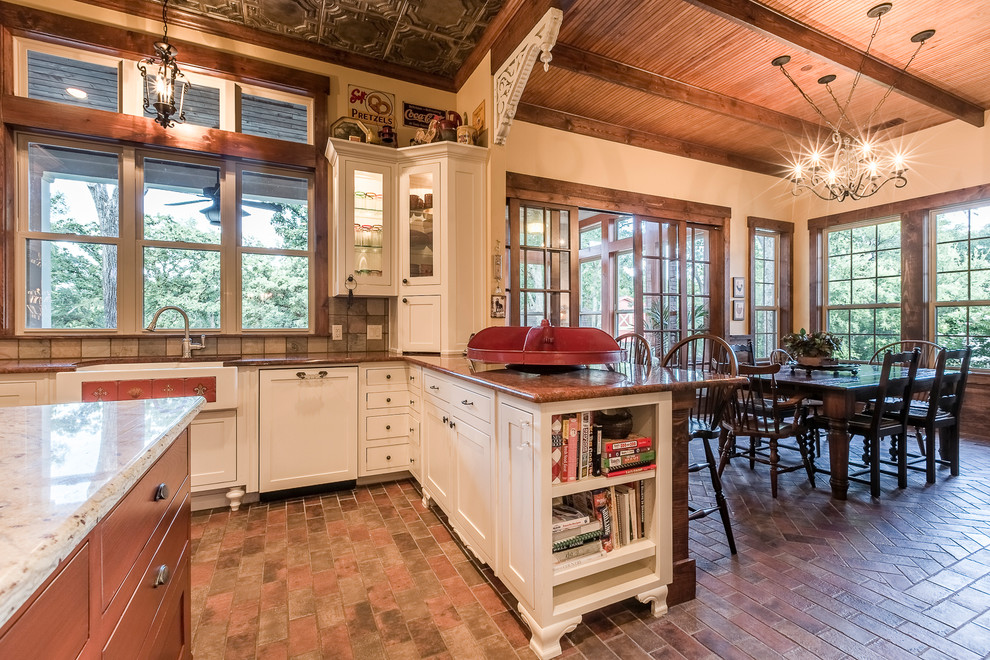 Foto på ett stort vintage kök, med en rustik diskho, skåp i shakerstil, vita skåp, granitbänkskiva, grått stänkskydd, stänkskydd i stenkakel, vita vitvaror, tegelgolv och en köksö