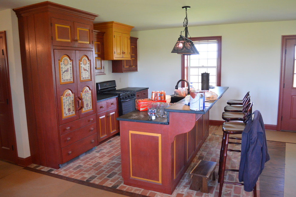 Exempel på ett stort lantligt linjärt kök med öppen planlösning, med en enkel diskho, luckor med upphöjd panel, röda skåp, bänkskiva i täljsten, tegelgolv, en köksö och integrerade vitvaror