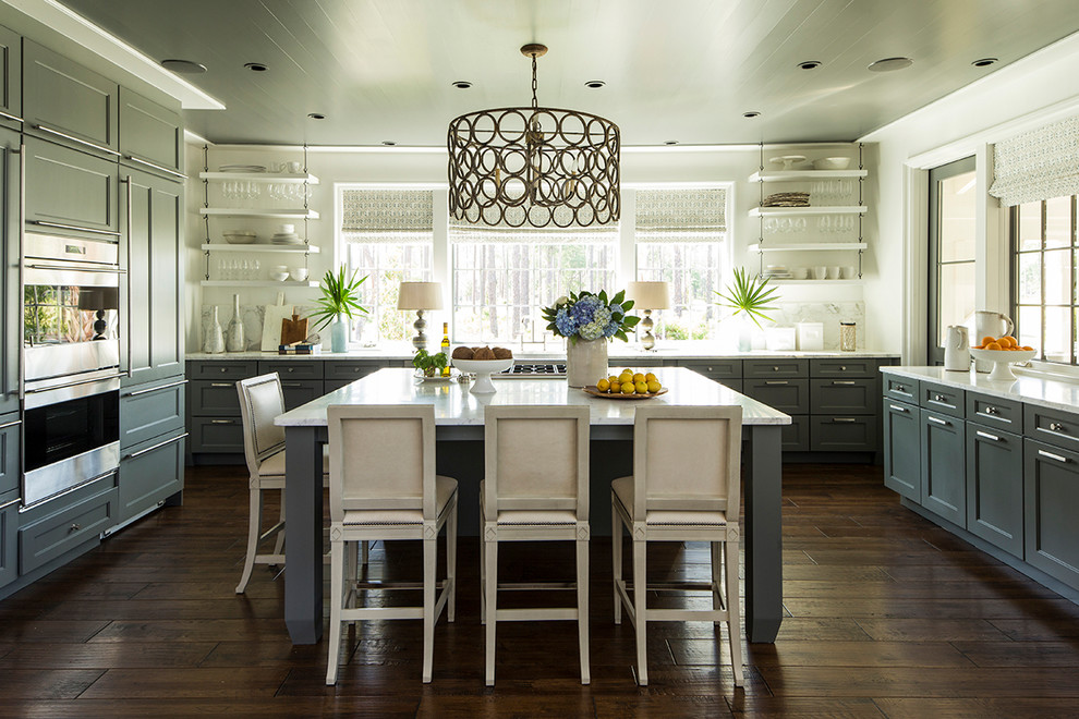 Foto di un cucina con isola centrale costiero con ante in stile shaker, ante blu, elettrodomestici in acciaio inossidabile, parquet scuro, pavimento marrone e top bianco