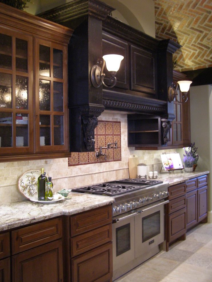 Elegant single-wall eat-in kitchen photo in Houston with glass-front cabinets, dark wood cabinets, beige backsplash and stone tile backsplash