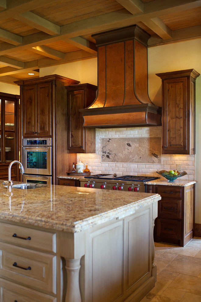 Example of a huge tuscan u-shaped limestone floor kitchen design in Dallas with raised-panel cabinets, dark wood cabinets, marble countertops, beige backsplash, stone tile backsplash, stainless steel appliances and an island