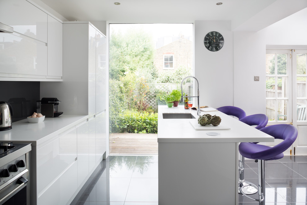 Zweizeilige Moderne Wohnküche mit Unterbauwaschbecken, flächenbündigen Schrankfronten, weißen Schränken, Küchenrückwand in Grau, Küchengeräten aus Edelstahl und Mineralwerkstoff-Arbeitsplatte in London