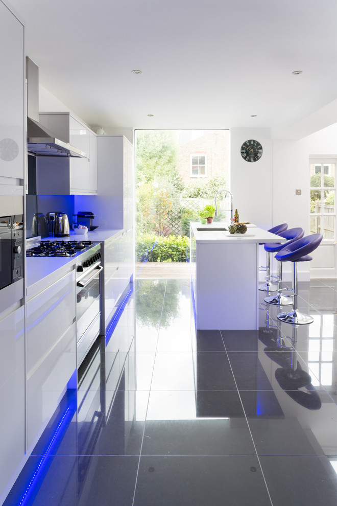 Moderne Küche mit Unterbauwaschbecken, flächenbündigen Schrankfronten, weißen Schränken, Küchenrückwand in Schwarz und Küchengeräten aus Edelstahl in London