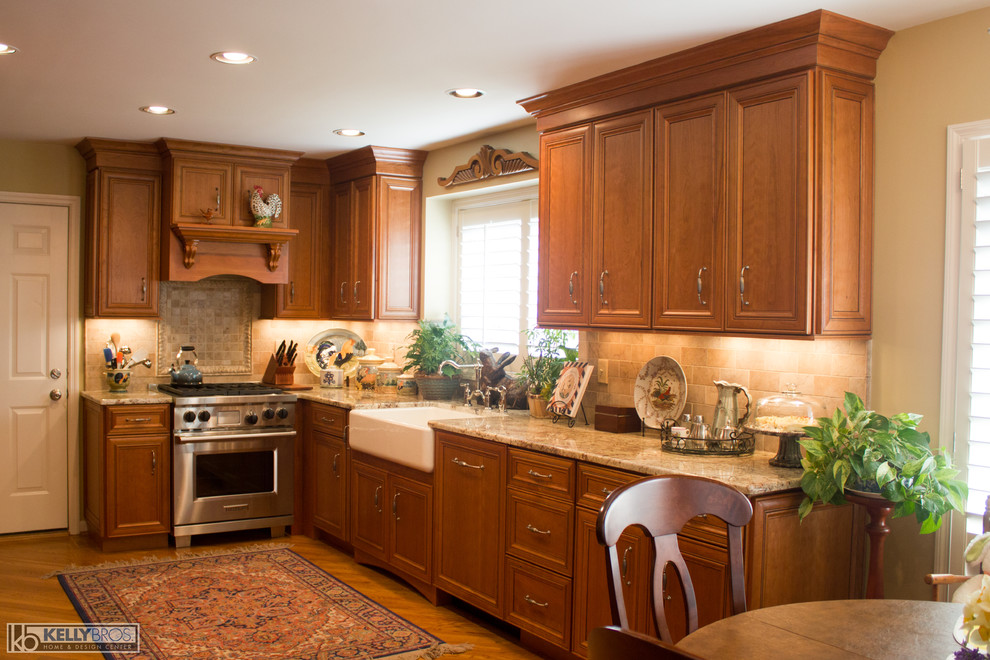 Example of a large classic single-wall light wood floor and brown floor eat-in kitchen design in Cincinnati with a farmhouse sink, flat-panel cabinets, medium tone wood cabinets, granite countertops, beige backsplash, stone tile backsplash, stainless steel appliances and no island