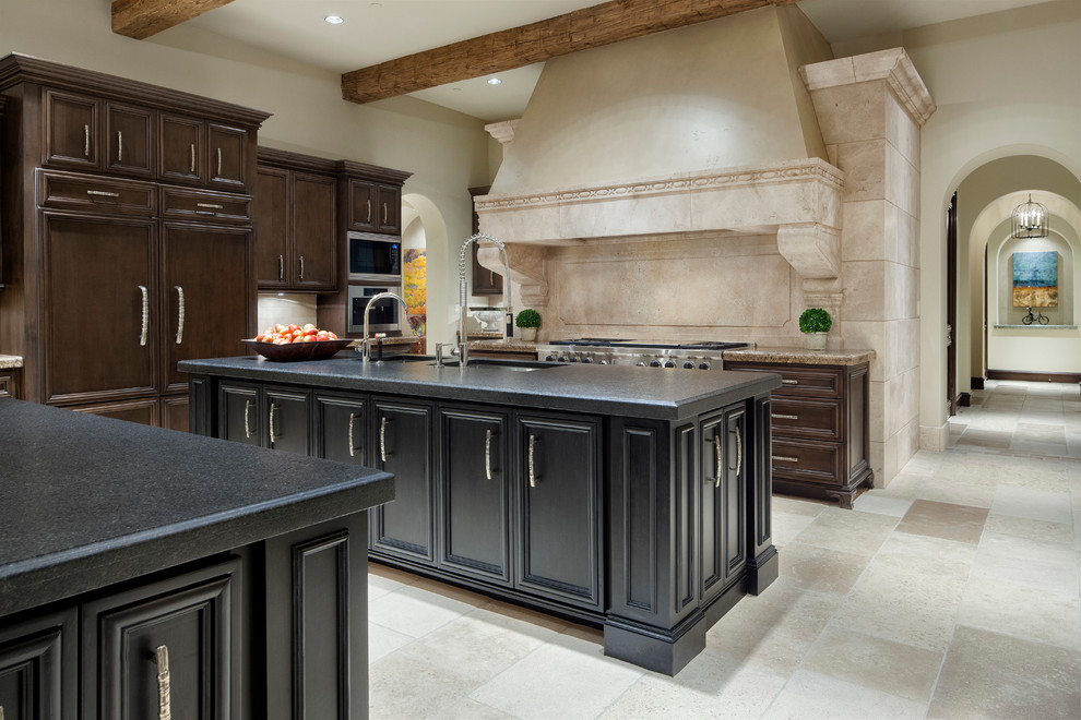 This is an example of a mediterranean kitchen in Austin with recessed-panel cabinets, dark wood cabinets, beige splashback and stainless steel appliances.