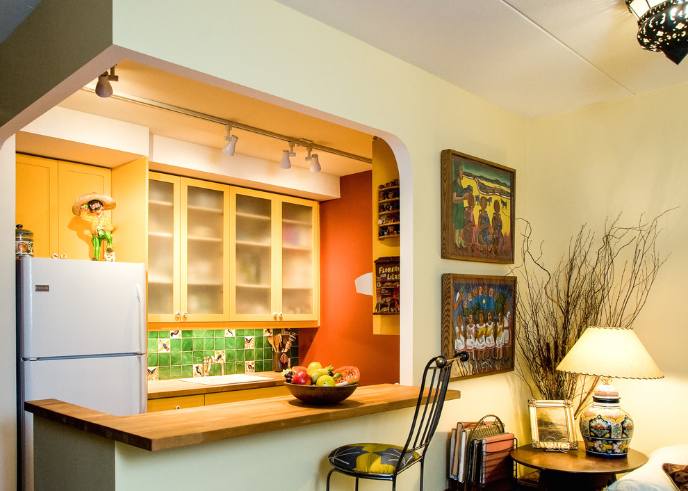 На фото: маленькая параллельная кухня в стиле фьюжн с обеденным столом, накладной мойкой, стеклянными фасадами, светлыми деревянными фасадами, деревянной столешницей, зеленым фартуком, фартуком из плитки мозаики, белой техникой и полуостровом для на участке и в саду