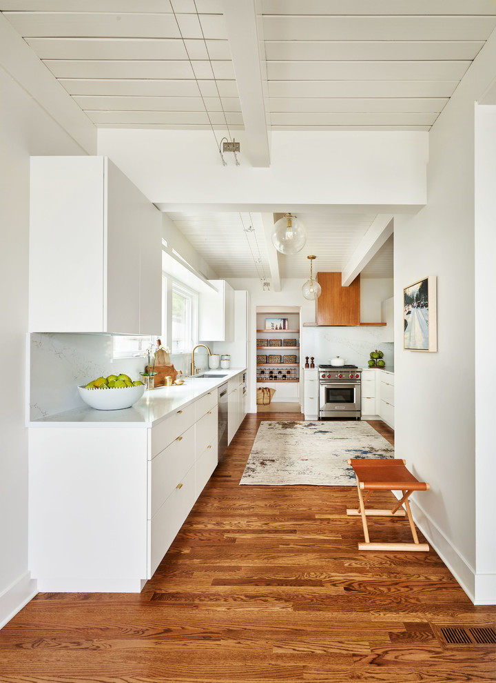 Inspiration for a large contemporary u-shaped kitchen pantry in Portland with a submerged sink, flat-panel cabinets, white cabinets, engineered stone countertops, white splashback, stone slab splashback, stainless steel appliances, medium hardwood flooring, no island, brown floors and white worktops.
