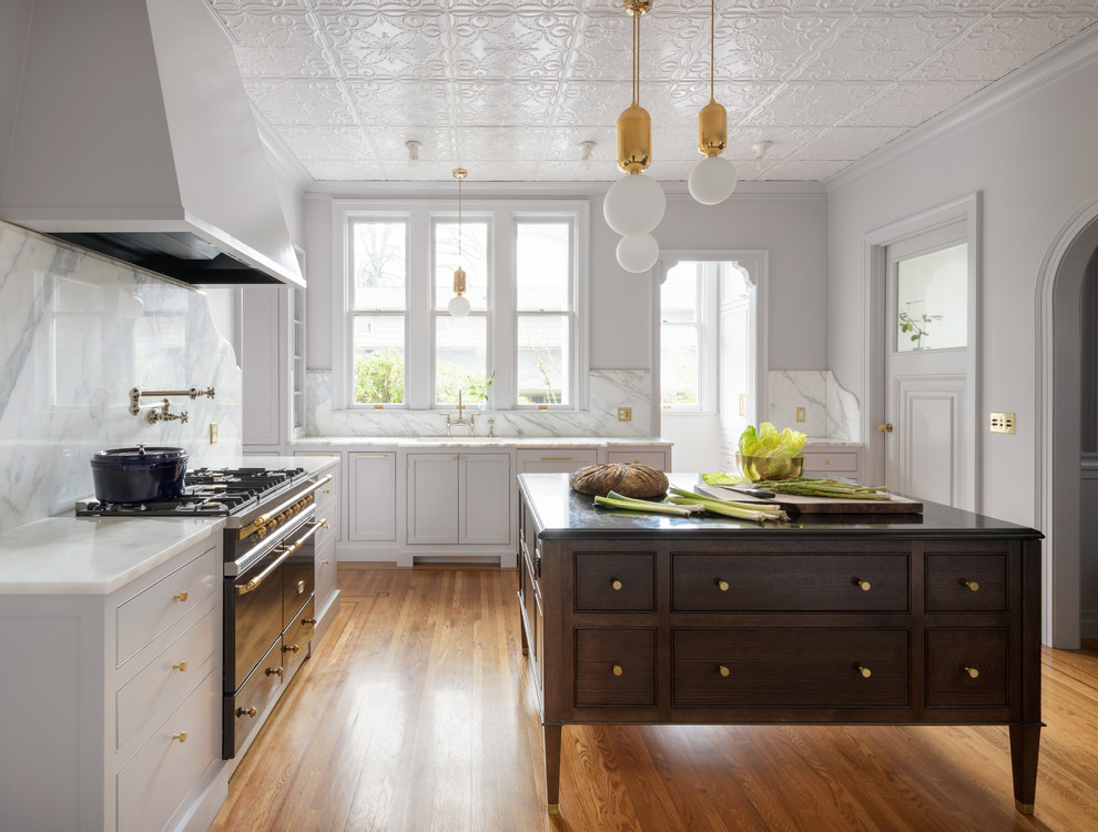 Esempio di una cucina classica con ante in stile shaker, ante grigie, paraspruzzi bianco, elettrodomestici neri, pavimento in legno massello medio, pavimento marrone e top bianco