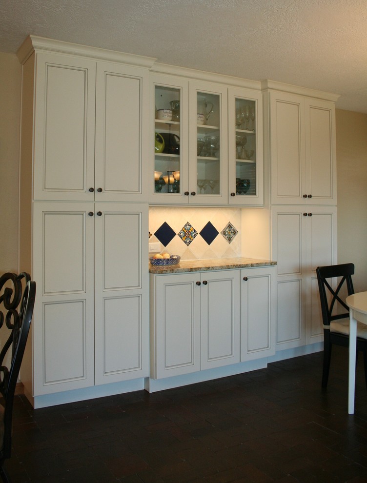 Idéer för ett mellanstort amerikanskt kök, med en undermonterad diskho, luckor med infälld panel, vita skåp, granitbänkskiva, vitt stänkskydd, stänkskydd i marmor, rostfria vitvaror, tegelgolv, en köksö och brunt golv