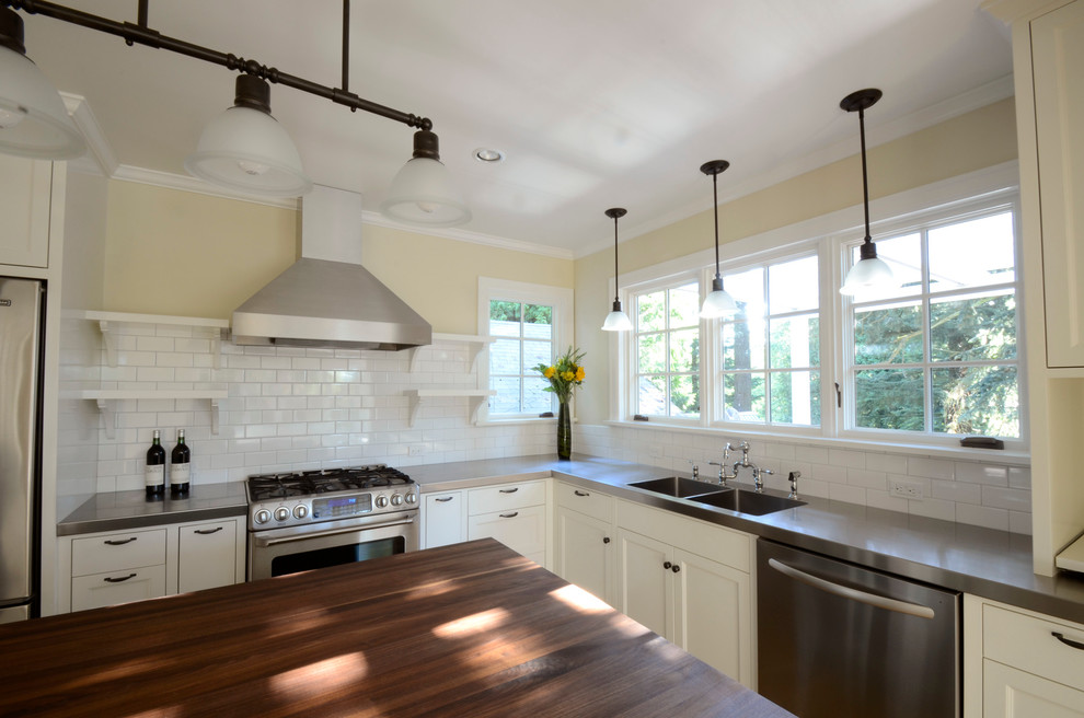 Elegant l-shaped eat-in kitchen photo in Portland with an integrated sink, recessed-panel cabinets, white cabinets, stainless steel countertops, white backsplash, subway tile backsplash and stainless steel appliances