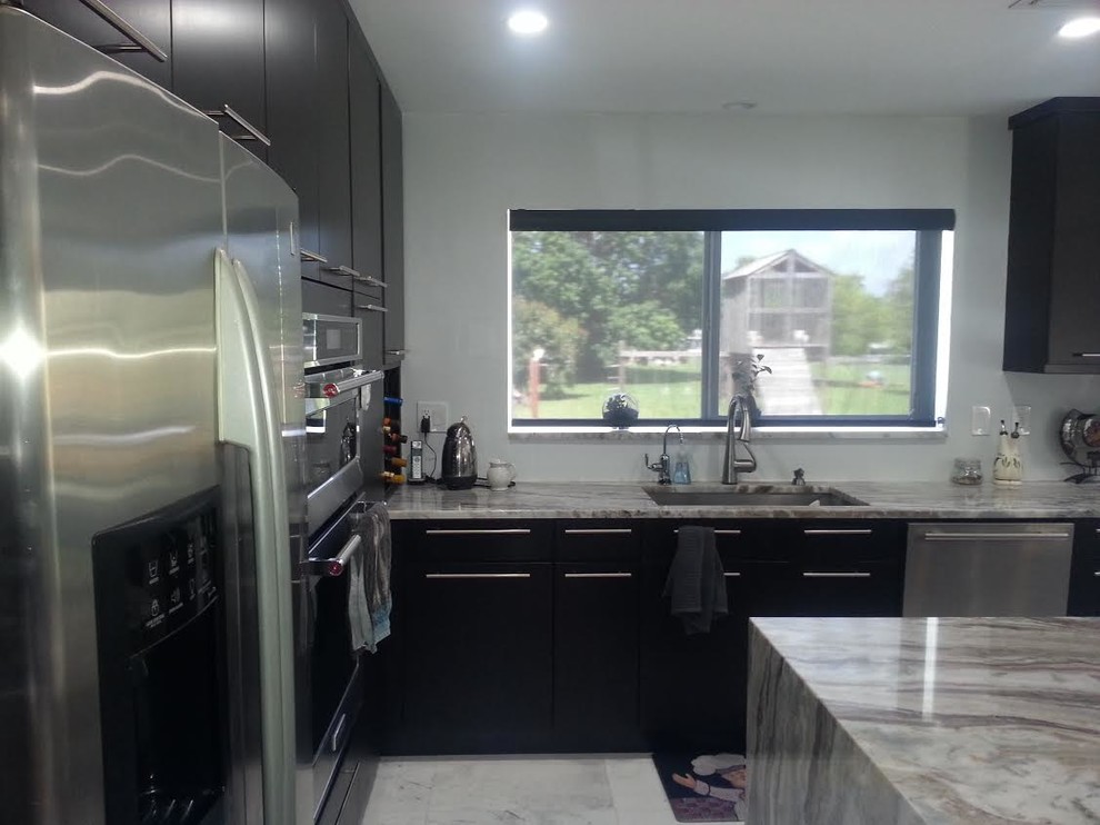 Immagine di una cucina minimal di medie dimensioni con lavello sottopiano, ante lisce, ante nere, top in granito, elettrodomestici in acciaio inossidabile, pavimento con piastrelle in ceramica e pavimento grigio