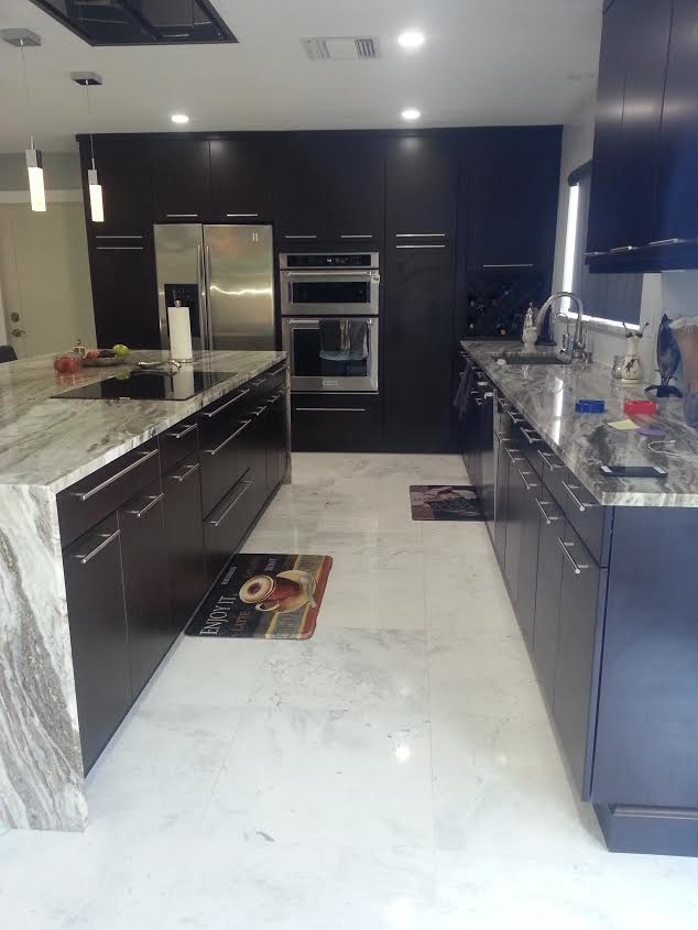 Modern inredning av ett mellanstort kök, med en undermonterad diskho, släta luckor, svarta skåp, granitbänkskiva, rostfria vitvaror, klinkergolv i keramik, en köksö och grått golv