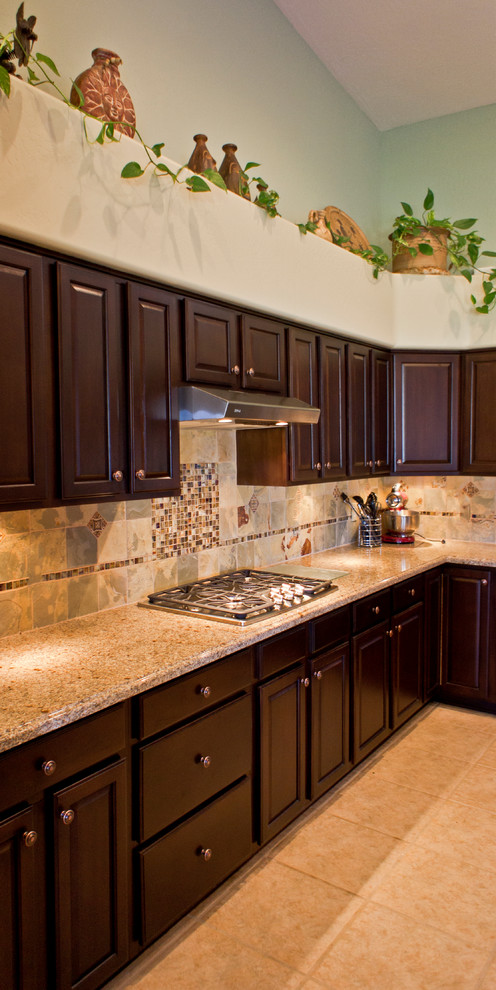 Exempel på ett klassiskt kök, med luckor med upphöjd panel, bruna skåp, granitbänkskiva, flerfärgad stänkskydd, rostfria vitvaror, klinkergolv i porslin och en köksö