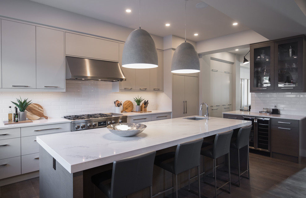This is an example of a contemporary kitchen in Calgary with a submerged sink, black cabinets, white splashback, metro tiled splashback, stainless steel appliances, dark hardwood flooring, an island, brown floors and white worktops.