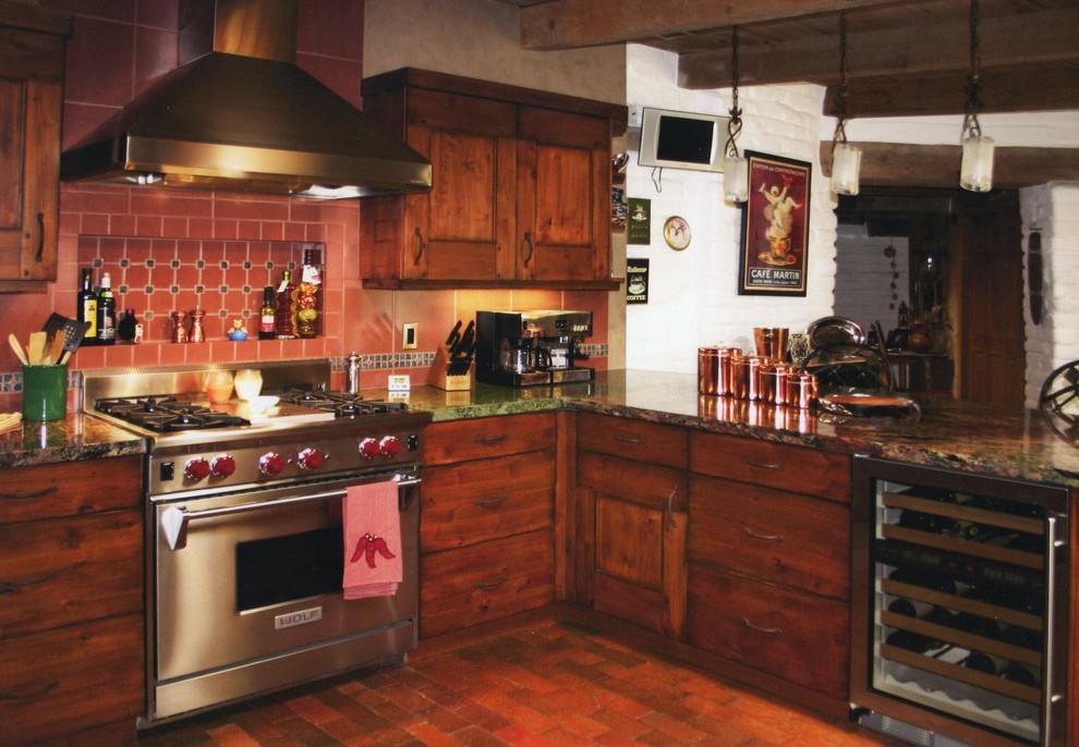 Photo of a medium sized rustic l-shaped open plan kitchen in Albuquerque with flat-panel cabinets, medium wood cabinets, granite worktops, red splashback, terracotta splashback, stainless steel appliances, brick flooring, a breakfast bar and red floors.