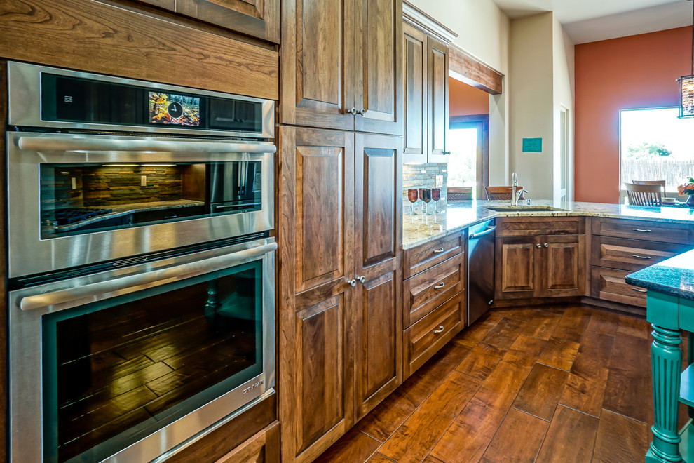 Bild på ett mellanstort amerikanskt kök, med luckor med upphöjd panel, skåp i mörkt trä, granitbänkskiva, flerfärgad stänkskydd, stänkskydd i stickkakel, rostfria vitvaror, mörkt trägolv, en köksö, brunt golv och en undermonterad diskho
