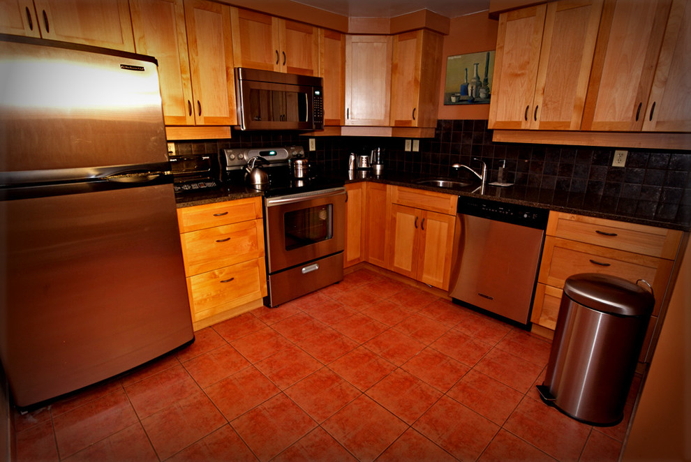 Bild på ett avskilt, mellanstort amerikanskt l-kök, med en undermonterad diskho, skåp i shakerstil, skåp i mellenmörkt trä, laminatbänkskiva, brunt stänkskydd, stänkskydd i porslinskakel, rostfria vitvaror och klinkergolv i terrakotta