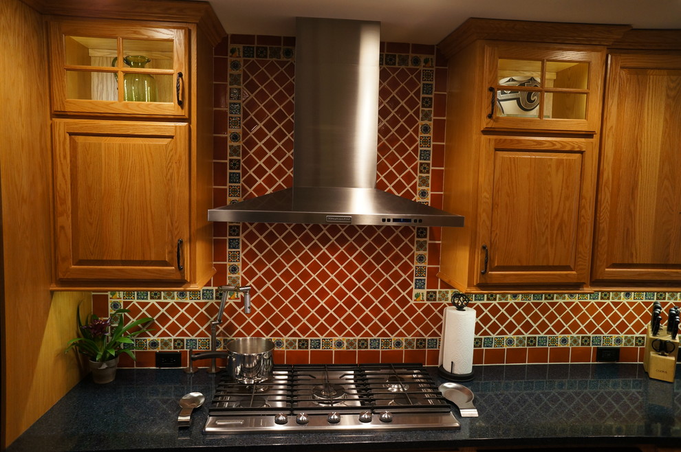 Amerikansk inredning av ett litet kök, med en undermonterad diskho, luckor med upphöjd panel, skåp i mellenmörkt trä, bänkskiva i kvarts, brunt stänkskydd, stänkskydd i terrakottakakel, rostfria vitvaror och linoleumgolv