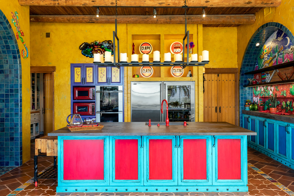 Immagine di un cucina con isola centrale american style con lavello sottopiano, ante con riquadro incassato, ante turchesi, elettrodomestici in acciaio inossidabile, pavimento in terracotta e pavimento multicolore