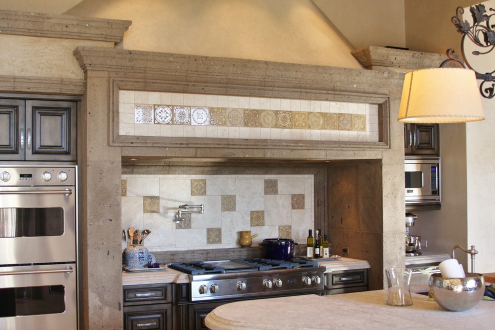 Foto på ett mellanstort amerikanskt kök, med luckor med upphöjd panel, skåp i slitet trä, bänkskiva i kalksten, beige stänkskydd, stänkskydd i stenkakel, rostfria vitvaror och flera köksöar