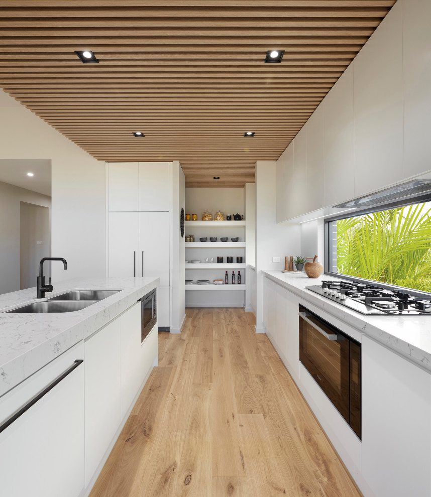 На фото: кухня среднего размера в современном стиле с врезной мойкой, островом и деревянным потолком