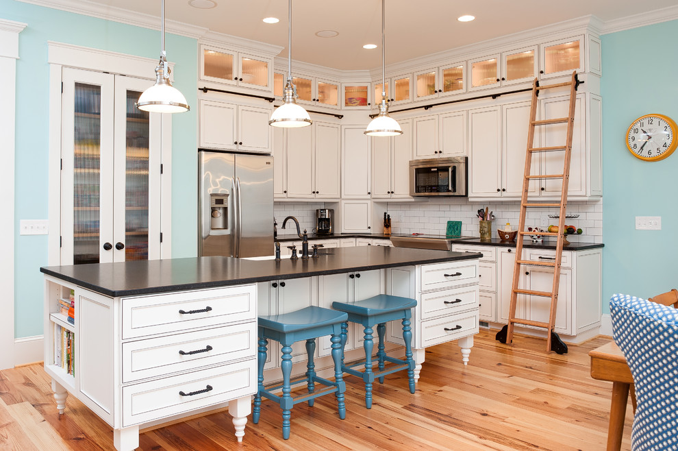 ウィルミントンにあるトラディショナルスタイルのおしゃれなL型キッチン (白いキッチンパネル、サブウェイタイルのキッチンパネル、淡色無垢フローリング、白いキャビネット) の写真