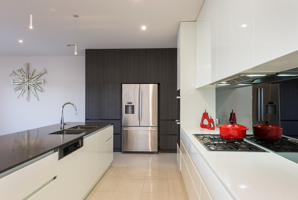 Große Moderne Küche mit weißen Schränken, Küchenrückwand in Grau, Glasrückwand, Küchengeräten aus Edelstahl, Keramikboden, Unterbauwaschbecken, flächenbündigen Schrankfronten und Kücheninsel in Melbourne