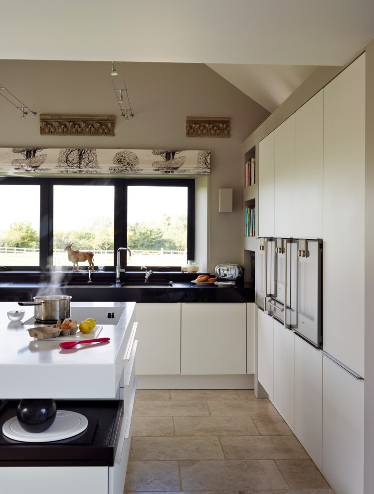 Imagen de cocina contemporánea pequeña con puertas de armario blancas, electrodomésticos de acero inoxidable, suelo de mármol y una isla