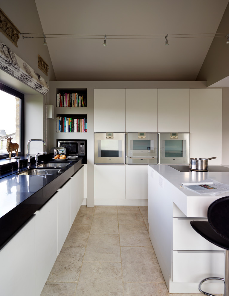 Ejemplo de cocina actual pequeña con fregadero de doble seno, puertas de armario blancas, electrodomésticos de acero inoxidable, suelo de mármol y una isla