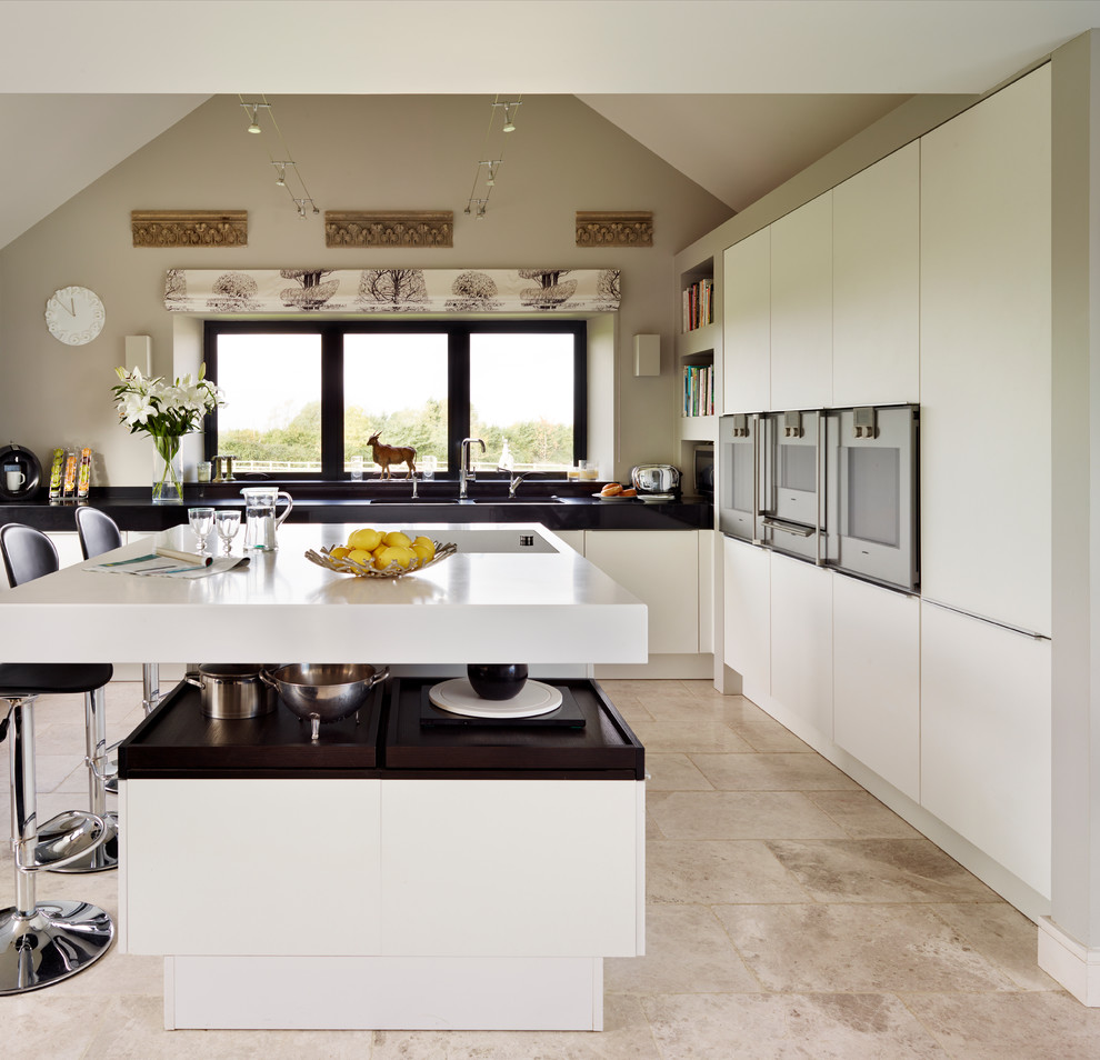 Ejemplo de cocina actual pequeña con puertas de armario blancas, electrodomésticos de acero inoxidable, suelo de mármol y una isla
