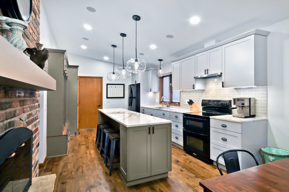 Inspiration for a mid-sized craftsman galley medium tone wood floor and brown floor eat-in kitchen remodel in Minneapolis with an undermount sink, shaker cabinets, white cabinets, quartz countertops, beige backsplash, ceramic backsplash, black appliances, an island and white countertops