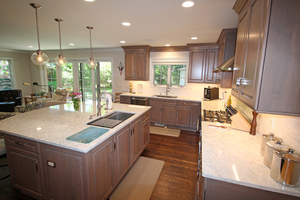 Example of a mid-sized classic l-shaped dark wood floor and brown floor eat-in kitchen design in Detroit with an undermount sink, raised-panel cabinets, light wood cabinets, quartz countertops, white backsplash, subway tile backsplash, stainless steel appliances and an island
