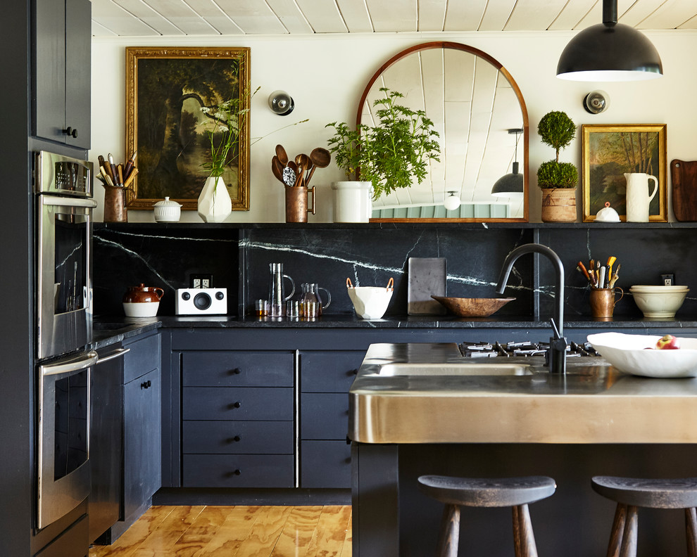 Imagen de cocina contemporánea con fregadero integrado, salpicadero negro, salpicadero de losas de piedra, electrodomésticos de acero inoxidable, suelo de madera en tonos medios, suelo marrón y encimeras negras