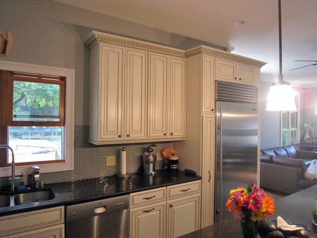 Example of a classic eat-in kitchen design in Chicago with an undermount sink, raised-panel cabinets, white cabinets, quartz countertops, mosaic tile backsplash, stainless steel appliances and an island