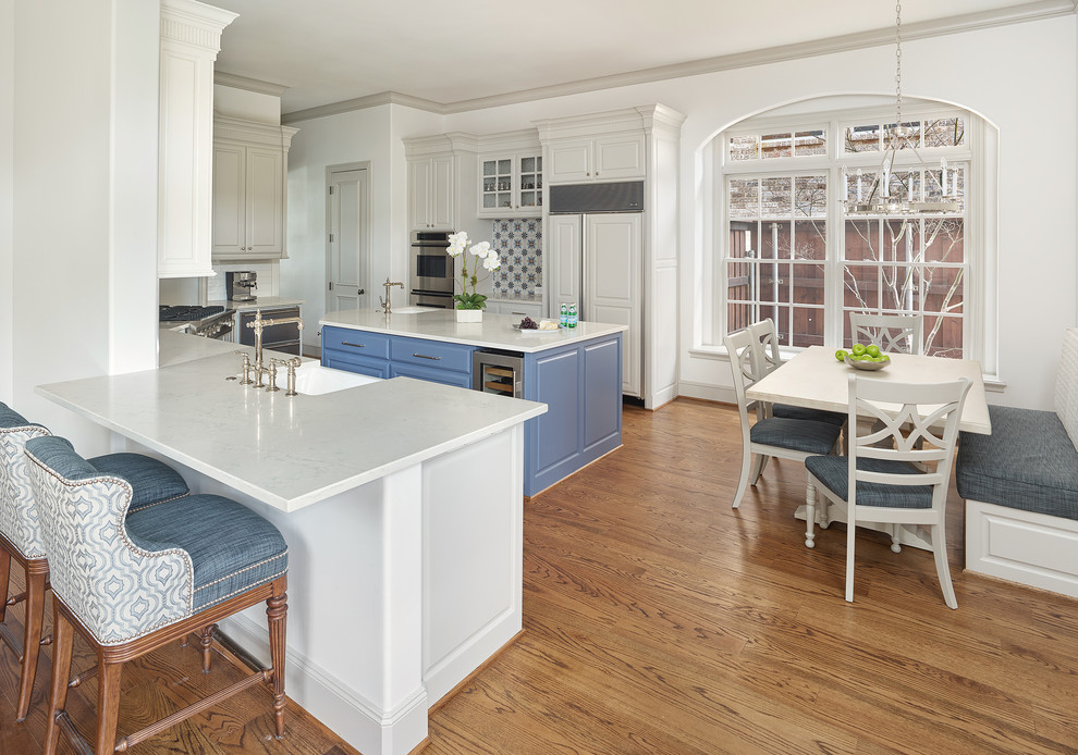 Inspiration for a timeless medium tone wood floor and brown floor eat-in kitchen remodel in Dallas with a farmhouse sink, raised-panel cabinets, white cabinets, paneled appliances, an island, white countertops and multicolored backsplash