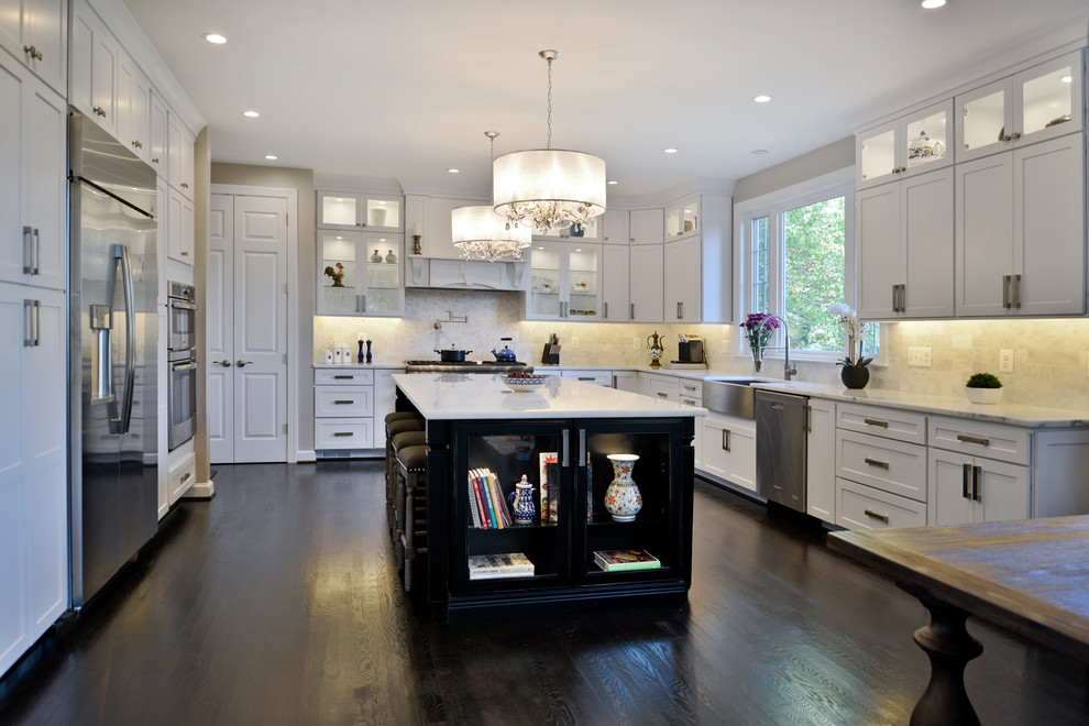 Photo of a large modern kitchen/diner in DC Metro with a belfast sink, white cabinets, quartz worktops, white splashback, travertine splashback, stainless steel appliances, dark hardwood flooring, an island, brown floors and white worktops.