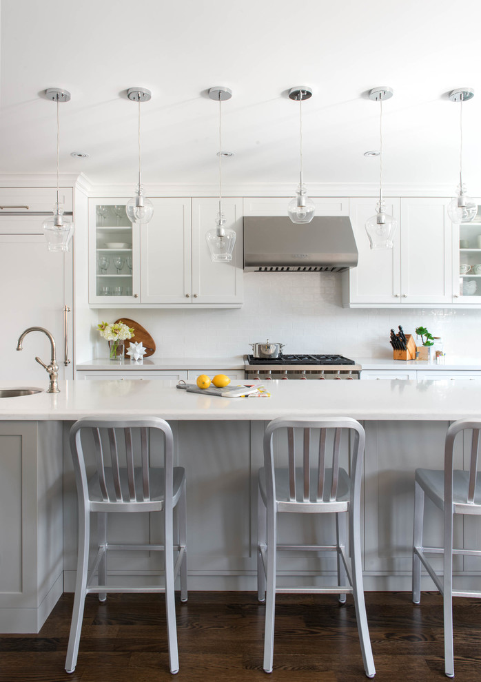 Große Klassische Wohnküche in L-Form mit Schrankfronten im Shaker-Stil, weißen Schränken, Küchenrückwand in Weiß, Rückwand aus Glasfliesen, Küchengeräten aus Edelstahl, dunklem Holzboden, Kücheninsel und Unterbauwaschbecken in Toronto