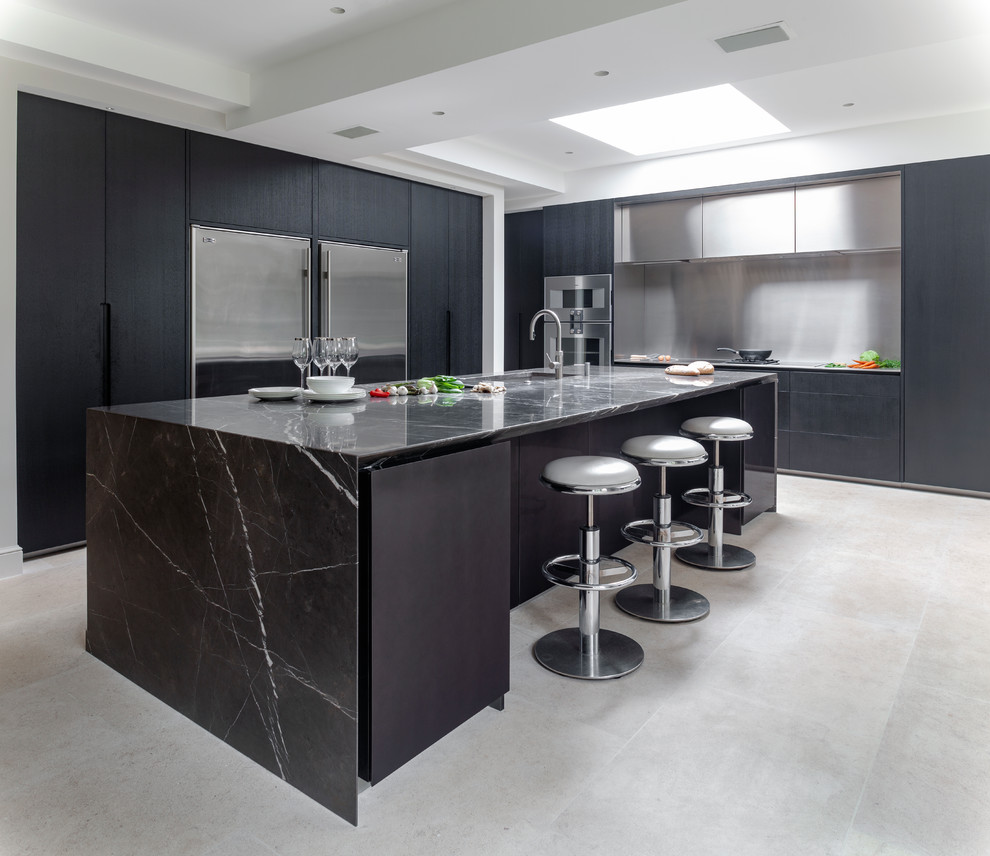 Inspiration för ett funkis svart svart l-kök, med en undermonterad diskho, släta luckor, svarta skåp, stänkskydd med metallisk yta, rostfria vitvaror, en köksö och grått golv