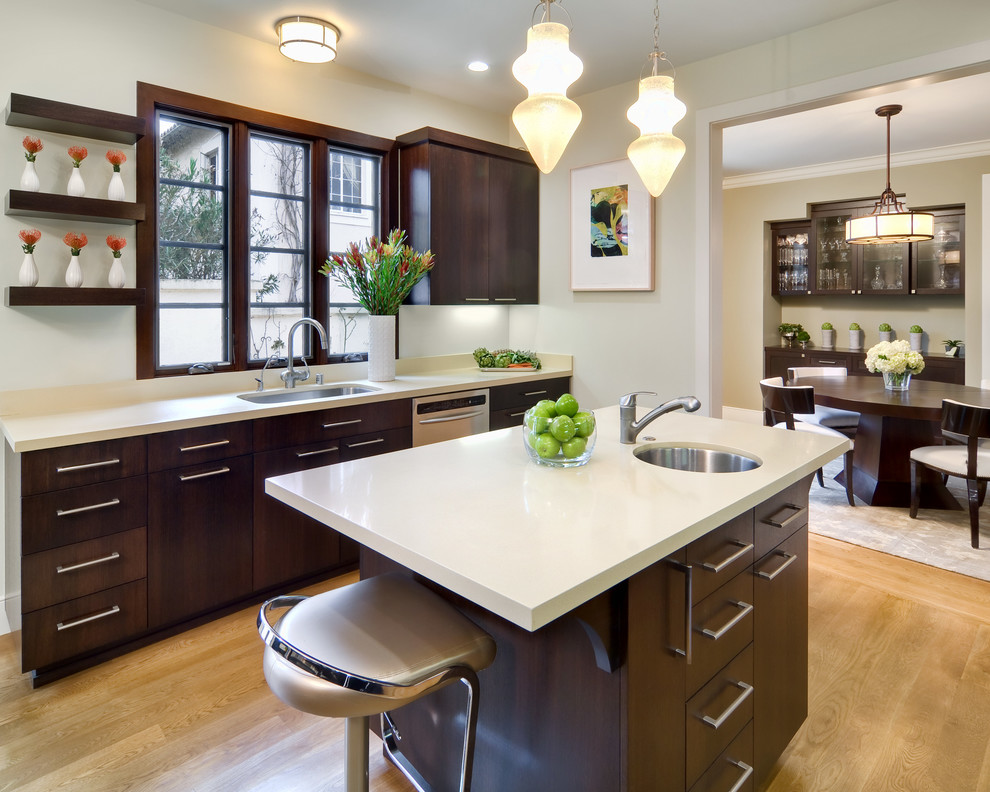 Example of a small tuscan galley light wood floor enclosed kitchen design in San Francisco with an undermount sink, flat-panel cabinets, dark wood cabinets, quartz countertops, stone slab backsplash, stainless steel appliances and an island