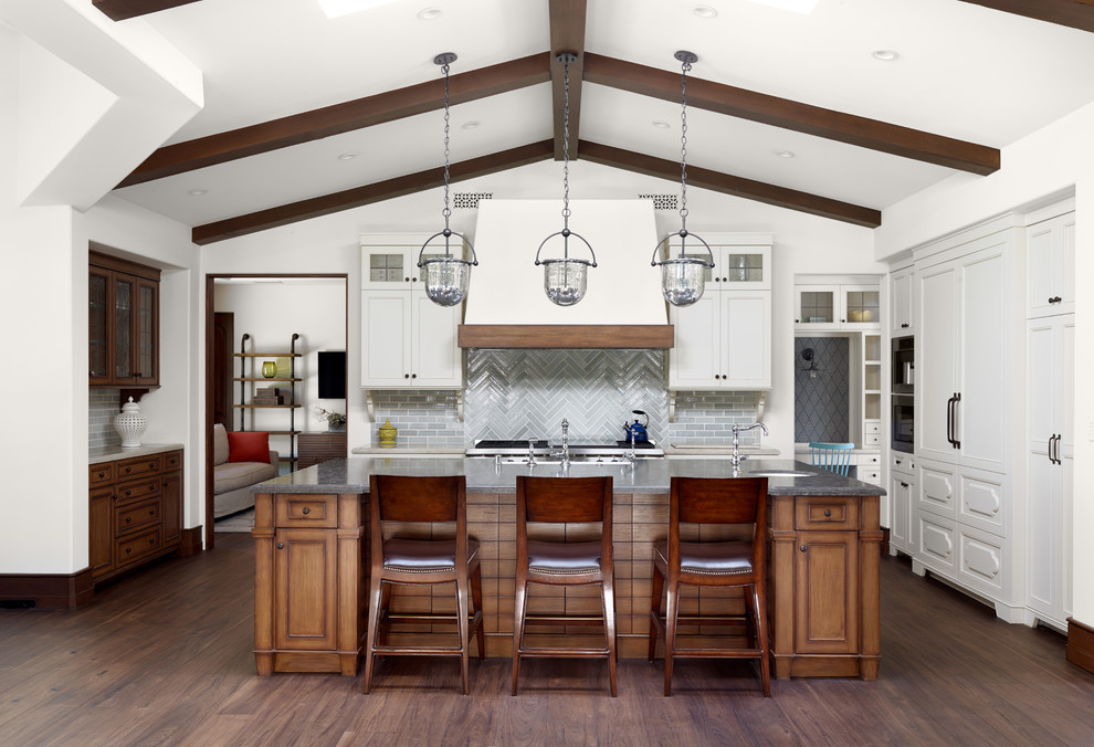 Kitchen - mediterranean l-shaped dark wood floor kitchen idea in Los Angeles with recessed-panel cabinets, white cabinets, gray backsplash, subway tile backsplash, paneled appliances and an island