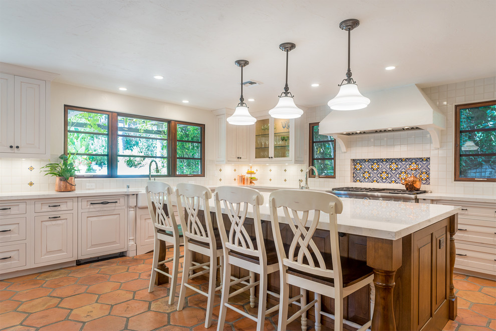 Large tuscan u-shaped terra-cotta tile kitchen photo in Los Angeles with a farmhouse sink, raised-panel cabinets, white cabinets, marble countertops, multicolored backsplash, cement tile backsplash, stainless steel appliances and an island