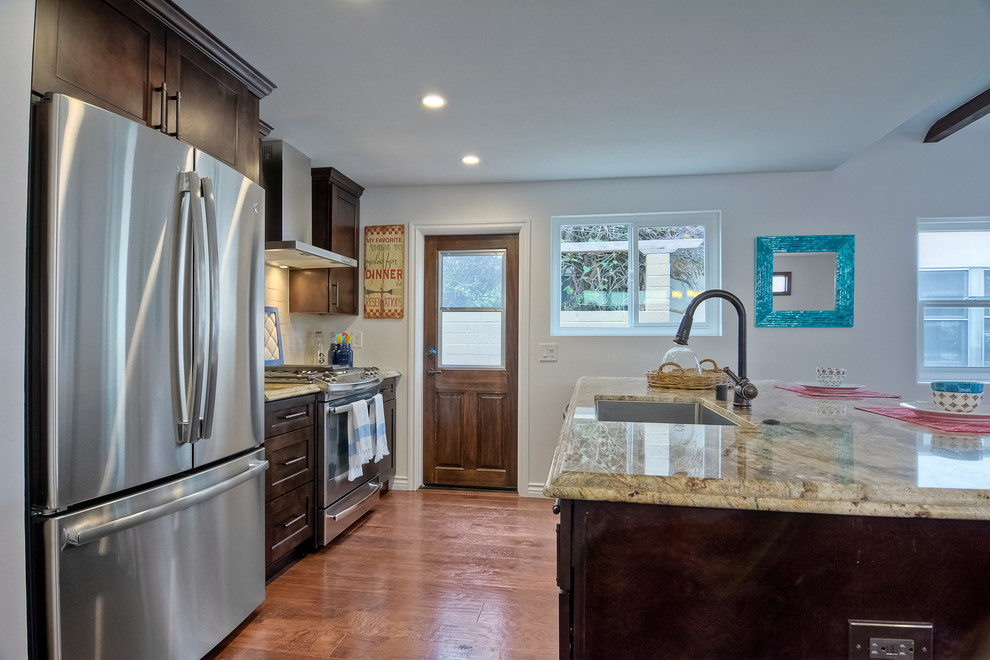 Bild på ett litet amerikanskt kök, med en undermonterad diskho, skåp i shakerstil, skåp i mörkt trä, marmorbänkskiva, beige stänkskydd, stänkskydd i stenkakel, rostfria vitvaror, mellanmörkt trägolv och en köksö