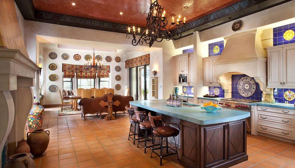 Example of a large tuscan l-shaped ceramic tile eat-in kitchen design in Tampa with concrete countertops, an island, a double-bowl sink, white cabinets, blue backsplash, ceramic backsplash, raised-panel cabinets and stainless steel appliances