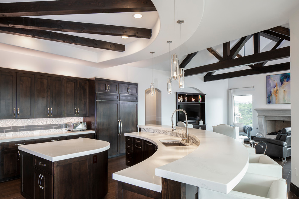Example of a large minimalist u-shaped dark wood floor and brown floor open concept kitchen design in Austin with a drop-in sink, flat-panel cabinets, brown cabinets, quartzite countertops, beige backsplash, porcelain backsplash, stainless steel appliances, two islands and white countertops