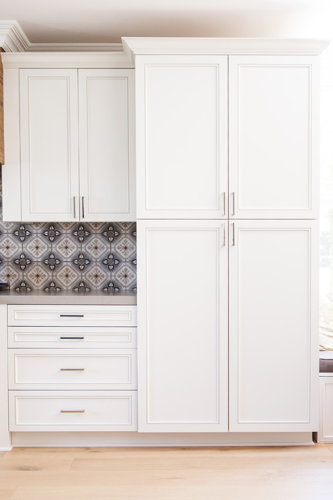 Photo of a medium sized classic l-shaped open plan kitchen in San Diego with a submerged sink, recessed-panel cabinets, white cabinets, quartz worktops, multi-coloured splashback, cement tile splashback, stainless steel appliances, light hardwood flooring, an island and beige floors.